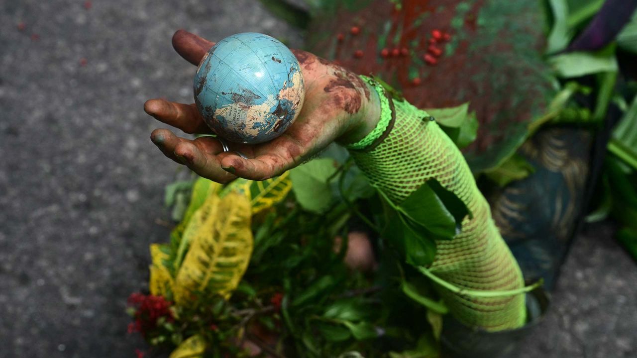 Un hombre indígena se acuesta en el suelo mientras sostiene un globo en la mano durante la "Marcha Global de Pueblos Indígenas". COP30. Brasil. Foto de Pablo PORCIUNCULA / AFP | Foto:AFP