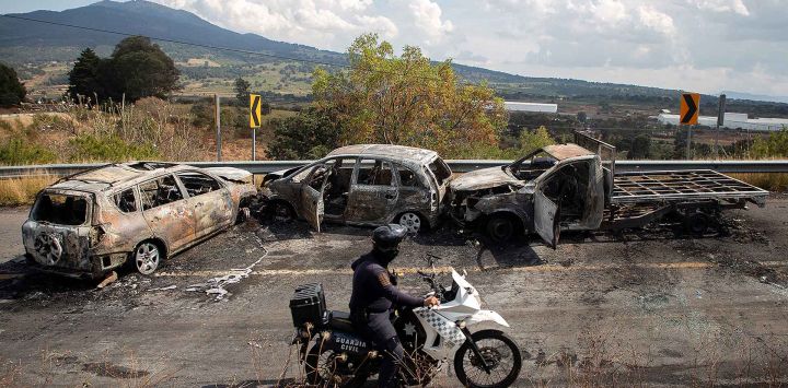 Inspeccionan el área donde cuatro vehículos fueron incendiados por presuntos miembros del crimen organizado en una carretera cerca de Quiroga, estado de Michoacán, México. Foto de Enrique CASTRO / AFP