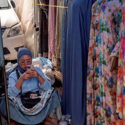 Una vendedora usa su celular mientras espera a los clientes en un puesto de ropa local en un mercado tradicional en Yakarta. Foto de BAY ISMOYO / AFP | Foto:AFP