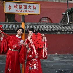 Una pareja con trajes tradicionales chinos posa para una foto frente a la Torre del Tambor en Beijing. Foto de Pedro PARDO / AFP | Foto:AFP