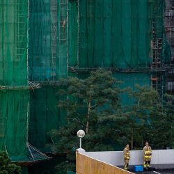 Los bomberos descansan en el podio de un aparcamiento junto al lugar del incendio que arrasó varios bloques de apartamentos en la urbanización Wang Fuk Court. Foto de Philip FONG / AFP | Foto:AFP