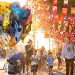 La gente camina bajo banderas nacionales de Laos y banderas del Partido Popular Revolucionario de Laos junto a globos que se venden en la calle en Vientián. Foto de AFP | Foto:AFP