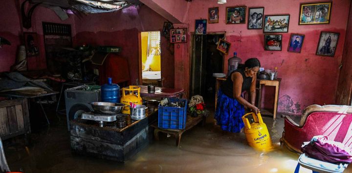 Un residente lleva un cilindro de GLP (gas licuado de petróleo) a través de una casa inundada tras las inundaciones repentinas provocadas por el ciclón Ditwah, en Wellampitiya, en las afueras de Colombo. Foto de Ishara S. KODIKARA / AFP
