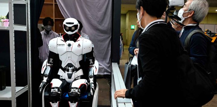 La gente observa un robot humanoide Kawasaki Kaleido mientras es retirado en carrito después de una demostración en la Exposición Internacional de Robots en Tokio. Foto de GREG BAKER / AFP