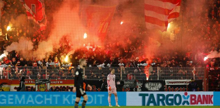 Aficionados del Union Berlin encienden bengalas durante el partido de octavos de final de la Copa de Alemania, en Berlín. Foto de Odd ANDERSEN / AFP