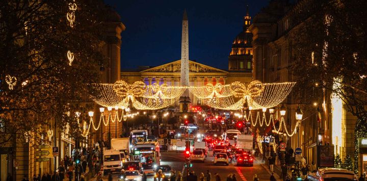 Peatones cruzan la Rue Royale con las iluminaciones navideñas y la Place de la Concorde al fondo en París. Foto de Dimitar DILKOFF / AFP