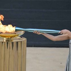 La actriz griega Mary Mina, interpretando el papel de la Suma Sacerdotisa, enciende la antorcha olímpica para los Juegos Olímpicos y Paralímpicos de Invierno Milán-Cortina. Foto de Angelos Tzortzinis / AFP | Foto:AFP