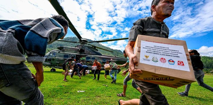 Residentes llevan suministros distribuidos por el personal de la fuerza aérea indonesia en las zonas afectadas por inundaciones en el distrito de Bener Meriah. Foto de CHAIDEER MAHYUDDIN / AFP