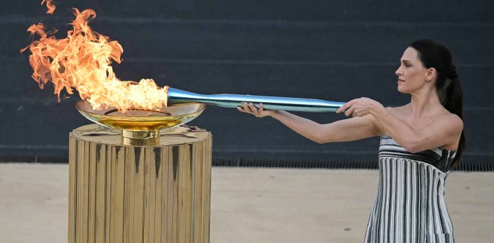 La actriz griega Mary Mina, interpretando el papel de la Suma Sacerdotisa, enciende la antorcha olímpica para los Juegos Olímpicos y Paralímpicos de Invierno Milán-Cortina. Foto de Angelos Tzortzinis / AFP