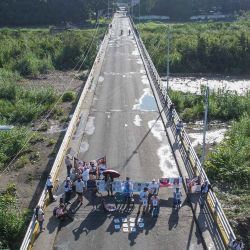 Familiares encadenados de ciudadanos colombianos detenidos en Venezuela, mientras sostienen fotos y bloquean el puente fronterizo internacional Simón Bolívar. Foto de Schneyder Mendoza / AFP  | Foto:AFP