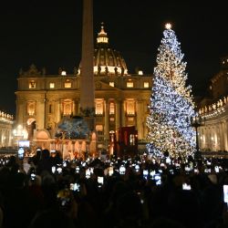 La gente toma fotos con sus teléfonos de la iluminación navideña en la Plaza de San Pedro, donde se inauguraron el árbol de Navidad y el belén en el Vaticano. | Foto:Tiziana Fabi / AFP