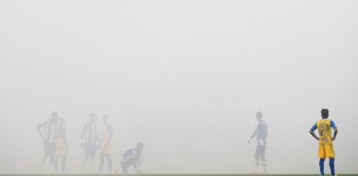 El defensor español de Estoril, Ricard Sánchez, y el resto de jugadores permanecen en el campo mientras el juego está suspendido temporalmente debido al humo de las bengalas de los aficionados durante el partido de fútbol de la Liga Portuguesa entre el FC Porto y el GD Estoril Praia en el estadio Dragao en Oporto.