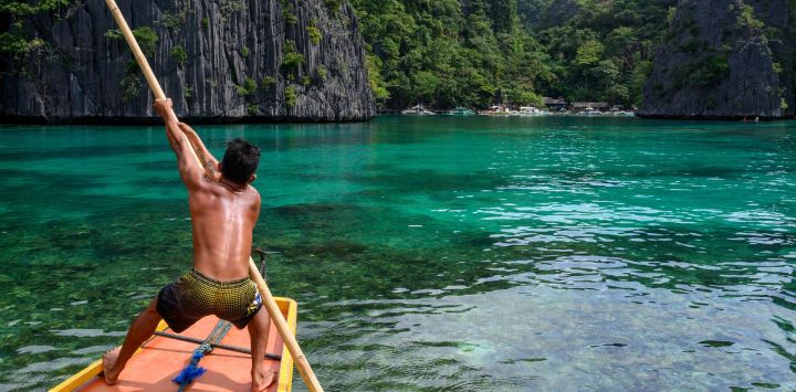Esta fotografía muestra a un barquero empujando su bote hacia la Laguna Verde, frente a la ciudad de Coron, en la provincia de Palawan, Filipinas.