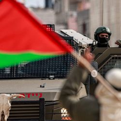 Un hombre palestino con su bandera nacional hace un gesto hacia un soldado israelí en el exterior del campo de refugiados palestinos de Nur Shams, en el norte de Cisjordania ocupado por Israel. | Foto:JAAFAR ASHTIYEH / AFP