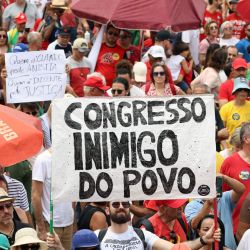 Un manifestante sostiene un cartel que dice "Congreso, enemigo del pueblo" durante una protesta contra el Congreso brasileño para rechazar un proyecto de ley que modificaría las penas por delitos contra la democracia, reduciendo así la condena del expresidente Jair Bolsonaro, y la reciente aprobación de una enmienda constitucional que incorpora la tesis del "Marco Temporal", que atenta contra los derechos territoriales indígenas, en Brasilia. | Foto:Sergio Lima / AFP