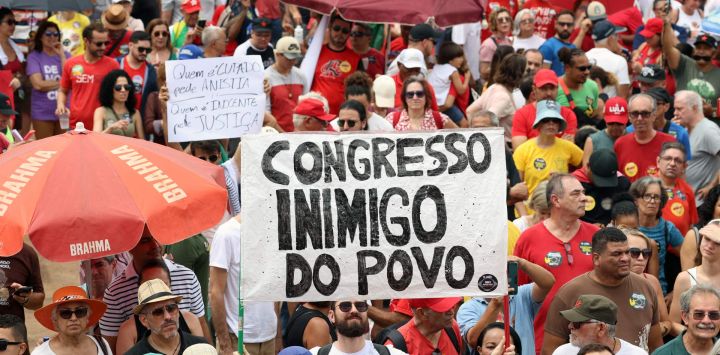 Un manifestante sostiene un cartel que dice "Congreso, enemigo del pueblo" durante una protesta contra el Congreso brasileño para rechazar un proyecto de ley que modificaría las penas por delitos contra la democracia, reduciendo así la condena del expresidente Jair Bolsonaro, y la reciente aprobación de una enmienda constitucional que incorpora la tesis del "Marco Temporal", que atenta contra los derechos territoriales indígenas, en Brasilia.