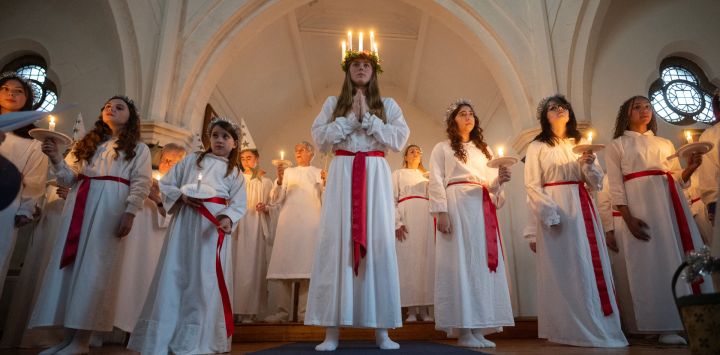 Florence Edwards (centro), interpretando a Lucía, se une al coro Lucía, compuesto por miembros de la Comunidad Nórdica Internacional de Liverpool, en el servicio sueco «Lucía: La Portadora de la Luz» en la iglesia Gustaf Adolfs Kyrka de Liverpool, noroeste de Inglaterra. En Suecia, Lucía es una de las tradiciones más significativas del calendario: Lucía conmemora a Lucía de Siracusa, una mártir de principios del siglo IV, que se dice que llevaba comida y ayuda a la gente con una corona de velas en la cabeza para tener las manos libres y poder llevar toda la comida que pudiera.