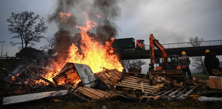 Miembros de la Coordinación Rural, sindicato agrícola francés, se reúnen junto a una hoguera durante un bloqueo agrícola de la autopista A63 en el intercambiador de Cestas, en Gironda, suroeste de Francia. Los agricultores franceses han estado protestando contra el protocolo gubernamental de sacrificio obligatorio de ganado vacuno afectado por la dermatosis nodular contagiosa (Dermatose nodulaire contagieuse), una enfermedad vírica detectada por primera vez en Francia en junio de 2025 que ha provocado el sacrificio de más de 3000 cabezas de ganado en más de 110 brotes en todo el país.