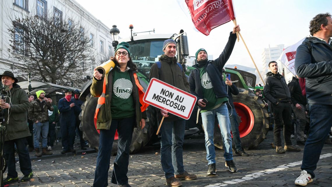 Protestors hold signs reading 'No to Mercosur' and France's main farmers union FNSEA (Federation Nationale des Syndicats d'Exploitants Agricoles) and Jeunes Agriculteurs (JA, Young Farmers) flags near the European Parliament at the Place du Luxembourg,…