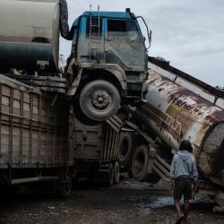 Camiones cisterna de aceite de palma se encuentran dañados tras una inundación repentina en un taller de reparación de vehículos en Aceh Tamiang, en el norte de Sumatra. | Foto:Yasuyoshi Chiba / AFP