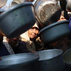 Palestinos desplazados se reúnen para recibir porciones de comida donadas en un comedor social en Khan Yunis, al sur de la Franja de Gaza. | Foto:Bashar Taleb / AFP