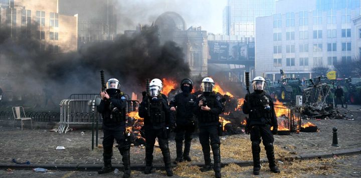 Agentes de policía evacuan la Plaza de Luxemburgo, cerca del Parlamento Europeo, durante una protesta de agricultores para denunciar las reformas de la Política Agrícola Común (PAC) y acuerdos comerciales como el Mercosur, en Bruselas.