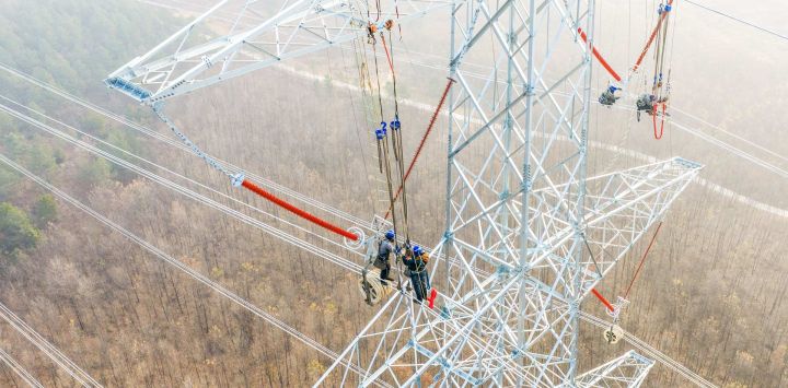 Imagen tomada con un dron de constructores trabajando en una línea de transmisión de energía eléctrica, en la provincia de Anhui, en el este de China.