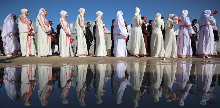 Novios hacen fila mientras unas 200 parejas se reúnen para una ceremonia nupcial multitudinaria bajo el lema "Amamos la vida a pesar del genocidio", organizada por la Fundación turca Al-Ribat en Al-Zawaida, en el centro de la Franja de Gaza.