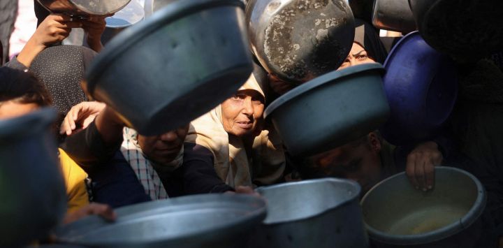 Palestinos desplazados se reúnen para recibir porciones de comida donadas en un comedor social en Khan Yunis, al sur de la Franja de Gaza.