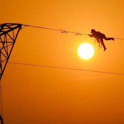 Imagen tomada con un dron de un constructor trabajando en una línea de transmisión de energía eléctrica, en la provincia de Anhui, en el este de China. | Foto:Xinhua/Zhou Mu