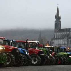 La foto muestra tractores agrícolas del departamento de Altos Pirineos estacionados frente a la Gruta de Massabielle, en el Santuario de Nuestra Señora de Lourdes, durante una misa del rosario con oraciones por los agricultores, con la Basílica de la Inmaculada Concepción como telón de fondo. Esto ocurrió tras una semana de protestas en todo el país del sector agrícola contra el protocolo gubernamental de sacrificio obligatorio de ganado afectado por la dermatosis nodular contagiosa (Dermatose nodulaire contagieuse), en Lourdes, suroeste de Francia. | Foto:BASTIEN ARBERET / AFP