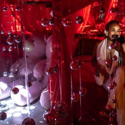 Un cliente usa su teléfono para tomarse una foto en una cama, en un espacio decorado para selfies dentro del baño del club de playa Lulu durante su inauguración durante el "Detty December" en Lagos. | Foto:OLYMPIA DE MAISMONT / AFP