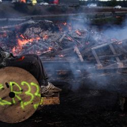 Un manifestante habla por teléfono frente a una hoguera antes de salir de la autopista A63 en Cestas, suroeste de Francia, durante una manifestación campesina para protestar contra el protocolo gubernamental de sacrificio obligatorio de ganado vacuno afectado por la dermatosis nodular contagiosa. | Foto:ROMAIN PERROCHEAU / AFP