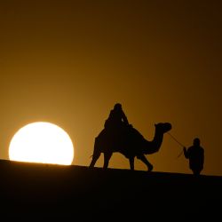 Un turista monta un camello de una joroba durante el atardecer en Al-Wakrah. | Foto:MAHMUD HAMS / AFP