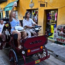 Una cochera conduce un nuevo carruaje eléctrico mientras transporta turistas por el centro histórico de Cartagena, Colombia. Los carruajes tradicionales tirados por caballos estarán prohibidos a partir del 29 de diciembre de 2025 en Cartagena, una joya turística de Colombia, según anunció la alcaldesa local. | Foto:MANUEL PEDRAZA / AFP