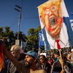 Un hombre sostiene una pintura del presidente estadounidense Donald Trump durante una protesta contra la intervención estadounidense en Venezuela, en Buenos Aires. El derrocado presidente venezolano, Nicolás Maduro, se declaró inocente de narcotráfico y otros cargos en una comparecencia desafiante ante un tribunal de Nueva York días después de ser secuestrado por fuerzas estadounidenses en un impactante allanamiento a su domicilio en Caracas. | Foto:Tomas Cuesta / AFP