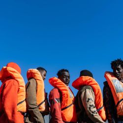 Migrantes hacen fila para subir a una lancha semirrígida (RHIB) mientras la tripulación del buque de rescate "Ocean Viking" los evacua del petrolero "Maridive 703" en la zona de búsqueda y rescate de aguas internacionales entre Malta y Túnez. | Foto:SAMEER Al-DOUMY / AFP