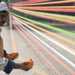 Un hombre prepara cuerdas de colores para cometas antes del Lohri, el festival de primavera en Amritsar, India. | Foto:Narinder Nanu / AFP