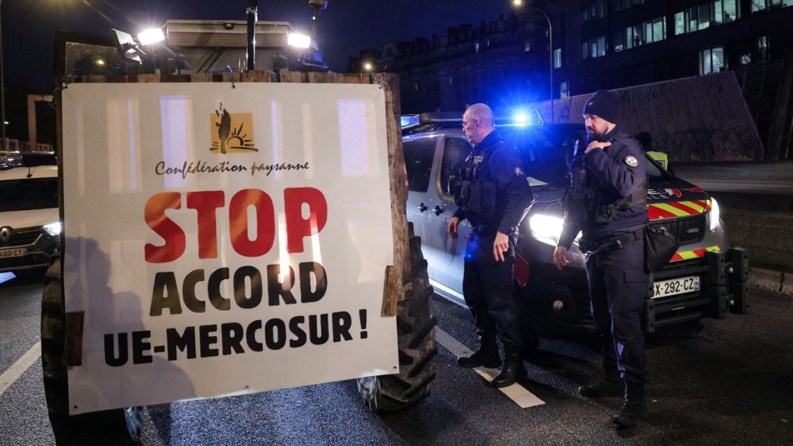 A demonstrator drives a tractor with a placard reading 'Stop the EU-MERCOSUR Agreement' as they take part in an action aiming at slowing down the traffic with their tractors on Paris' ring road to push France's government to block the Mercosur trade…