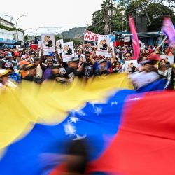 Manifestantes ondean una bandera venezolana gigante durante una manifestación en apoyo al derrocado presidente venezolano, Nicolás Maduro, en Caracas. El Departamento de Estado de EE. UU. instó a los estadounidenses en Venezuela a abandonar el país  | Foto:JUAN BARRETO / AFP