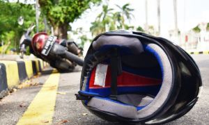 Casco en el pavimiento con moto detrás