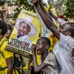 Jóvenes partidarios del actual presidente de Uganda y candidato presidencial del Movimiento de Resistencia Nacional (MRN), Yoweri Museveni, sostienen carteles electorales y corean consignas mientras hacen fila para ingresar al recinto de la manifestación antes del mitin de cierre de campaña del partido previo a las elecciones generales ugandesas. | Foto:AFP