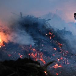 Un agricultor francés pasa junto a una fogata en una rotonda como parte de las protestas nacionales contra el acuerdo UE-Mercosur y la gestión gubernamental de la epidemia de dermatitis nodular contagiosa (DNC), en el puerto de Le Havre, noroeste de Francia. | Foto:LOU BENOIST / AFP