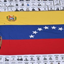 Un hombre toma fotografías de retratos de presos políticos durante una manifestación de familiares en la Universidad Central de Venezuela en Caracas. Venezuela anunció la liberación de decenas de presos políticos, mientras organizaciones de derechos humanos cuestionaban las cifras y sus familiares exigían liberaciones más rápidas tras el derrocamiento del autócrata Nicolás Maduro por parte de las fuerzas militares estadounidenses. | Foto:JUAN BARRETO / AFP