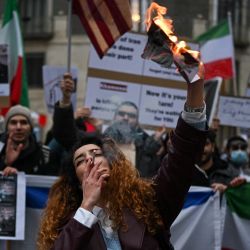 Un manifestante antirrégimen iraní enciende un cigarrillo con un papel encendido que representa a Ali Khamenei, líder supremo de Irán, durante una concentración frente al consulado estadounidense en Milán. | Foto:PIERO CRUCIATTI / AFP