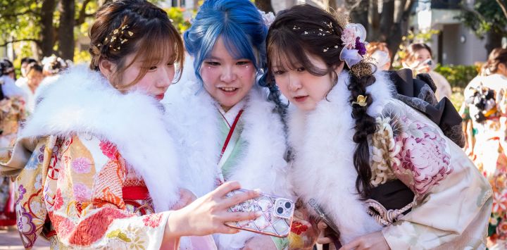 Mujeres vestidas con kimonos posan para una foto con su teléfono móvil a su llegada a una ceremonia en el Todoroki Arena para conmemorar el "Día de la Mayoría de Edad", en honor a quienes cumplen 20 años este año, en Kawasaki, prefectura de Kanagawa, Japón. 