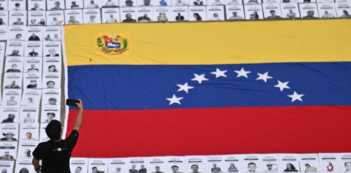 Un hombre toma fotografías de retratos de presos políticos durante una manifestación de familiares en la Universidad Central de Venezuela en Caracas. Venezuela anunció la liberación de decenas de presos políticos, mientras organizaciones de derechos humanos cuestionaban las cifras y sus familiares exigían liberaciones más rápidas tras el derrocamiento del autócrata Nicolás Maduro por parte de las fuerzas militares estadounidenses.
