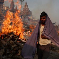 Un crematorio de la comunidad Dom pasa junto a las piras funerarias que arden en el Ghat Manikarnika, a orillas del río Ganges, en Varanasi, India. | Foto:NIHARIKA KULKARNI / AFP