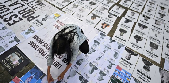 Una mujer participa en una manifestación publicando el retrato de un preso político en la Universidad Central de Venezuela en Caracas. Venezuela anunció la liberación de decenas de presos políticos, mientras organizaciones de derechos humanos cuestionaban las cifras y sus familiares exigían liberaciones más rápidas tras el derrocamiento del autócrata Nicolás Maduro por parte de las fuerzas militares estadounidenses.