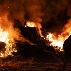 Un agricultor pasa junto a un incendio en una rotonda en Quimper, al oeste de Francia, durante un bloqueo agrícola para protestar contra el protocolo gubernamental de sacrificio obligatorio de ganado afectado por la dermatosis nodular contagiosa (DNC) y el acuerdo comercial entre la UE y el Mercosur. | Foto:FRED TANNEAU / AFP